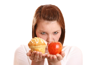Photo of a young adult woman keeping an apple and a muffin.